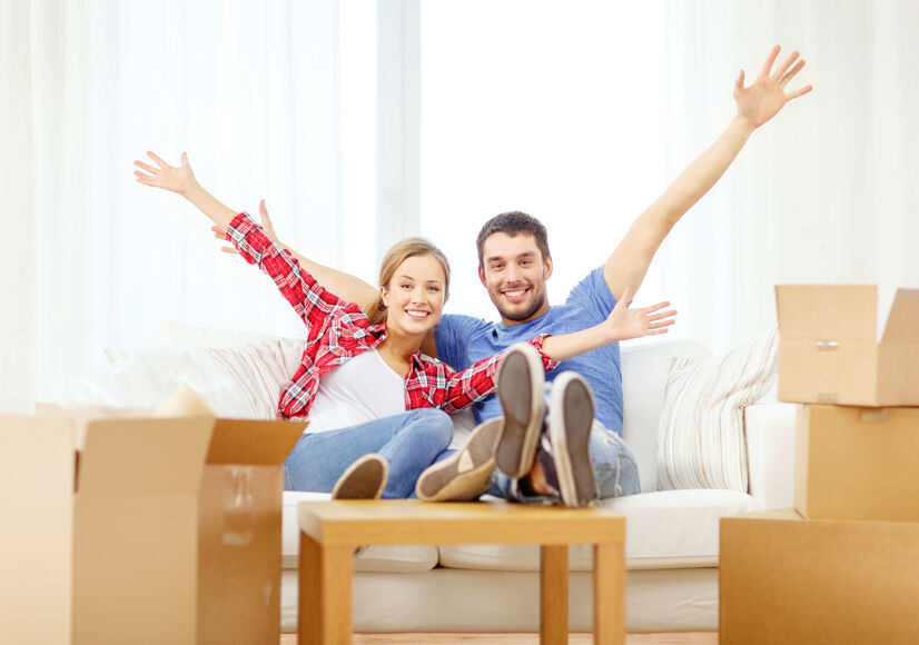 smiling couple relaxing on sofa in new home