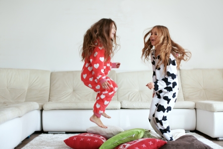 children in pajamas jumping around in the living room 