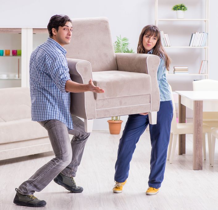 Man and woman moving armchair in the living room